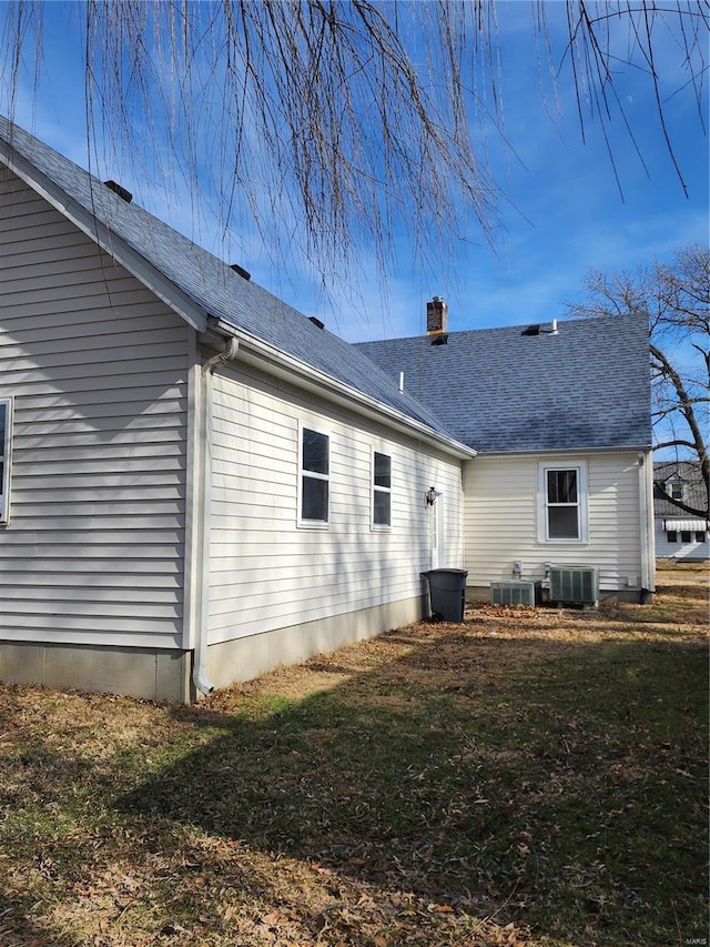 back of house featuring central AC unit and a lawn