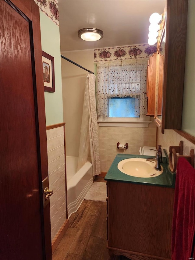 bathroom with hardwood / wood-style floors, vanity, shower / tub combo, and tile walls