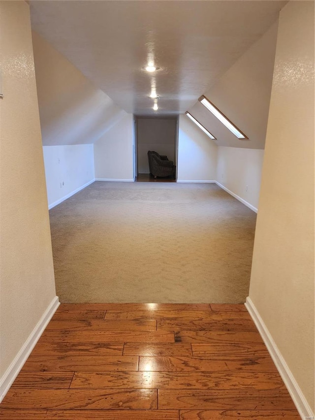 bonus room with wood-type flooring and lofted ceiling with skylight