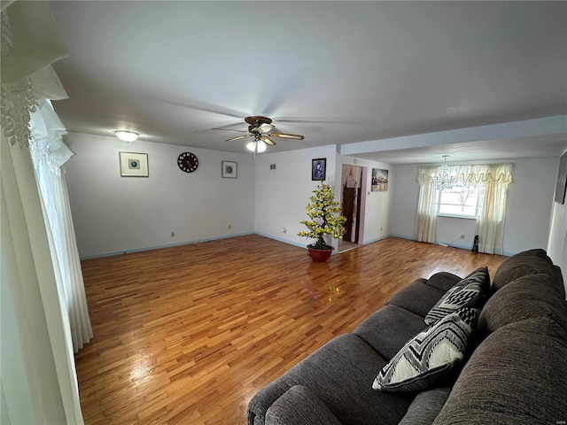 living room featuring ceiling fan with notable chandelier and light hardwood / wood-style floors