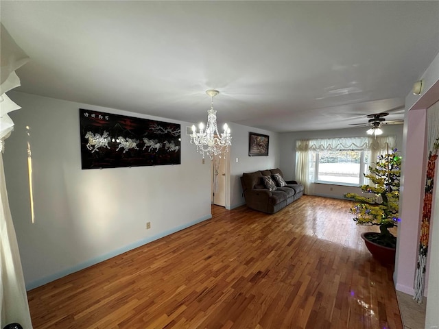 unfurnished living room featuring ceiling fan with notable chandelier and hardwood / wood-style floors