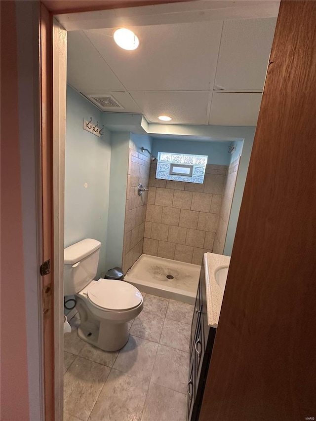 bathroom featuring vanity, tile patterned flooring, toilet, and tiled shower