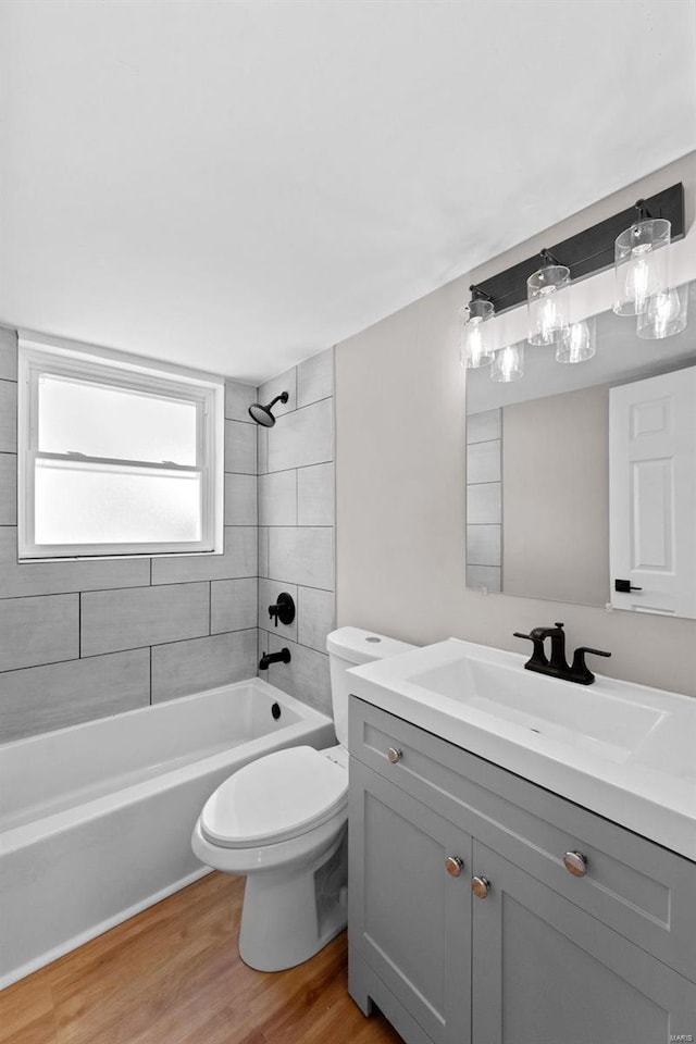 bathroom featuring  shower combination, toilet, wood finished floors, and vanity