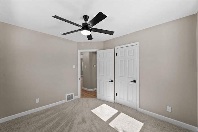 unfurnished bedroom with baseboards, visible vents, ceiling fan, and light colored carpet