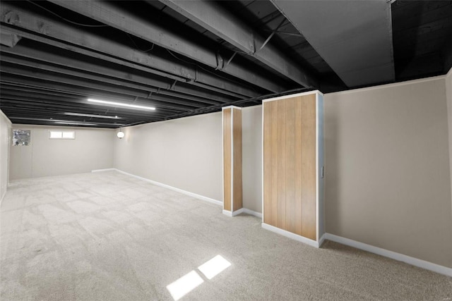 below grade area featuring light carpet and baseboards