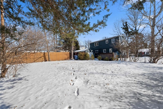 snowy yard featuring fence