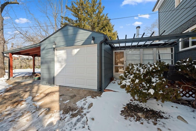 snow covered garage with driveway, a garage, and a carport