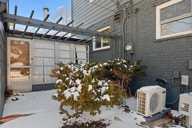 snow covered property featuring ac unit and brick siding