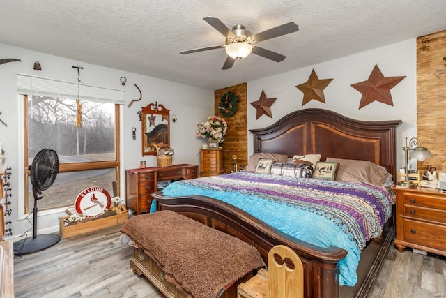 bedroom with ceiling fan, light hardwood / wood-style floors, and a textured ceiling