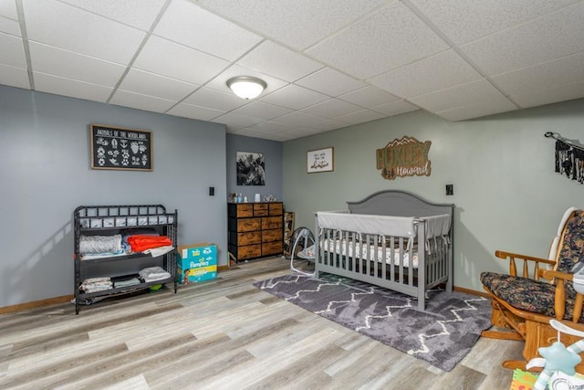 bedroom featuring a drop ceiling and light wood-type flooring