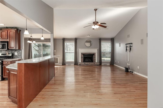 kitchen with pendant lighting, a healthy amount of sunlight, appliances with stainless steel finishes, and a fireplace