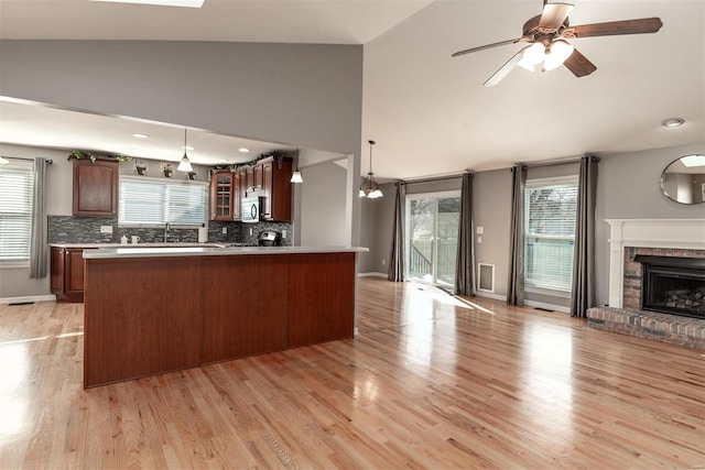 kitchen with light wood-type flooring, backsplash, a fireplace, and decorative light fixtures