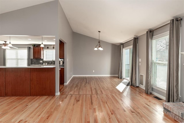 kitchen featuring pendant lighting, backsplash, light hardwood / wood-style floors, vaulted ceiling, and kitchen peninsula