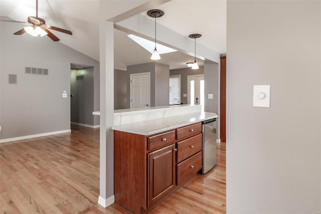 kitchen featuring vaulted ceiling, pendant lighting, dishwashing machine, ceiling fan, and light wood-type flooring