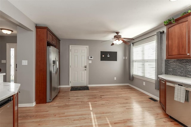 kitchen featuring appliances with stainless steel finishes, decorative backsplash, ceiling fan, and light hardwood / wood-style flooring