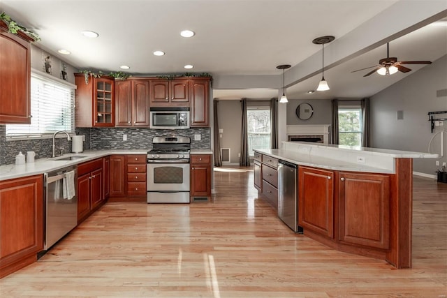 kitchen featuring sink, light hardwood / wood-style flooring, stainless steel appliances, decorative backsplash, and decorative light fixtures