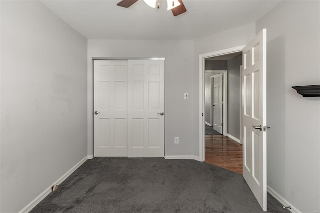 unfurnished bedroom with ceiling fan, dark carpet, and a closet