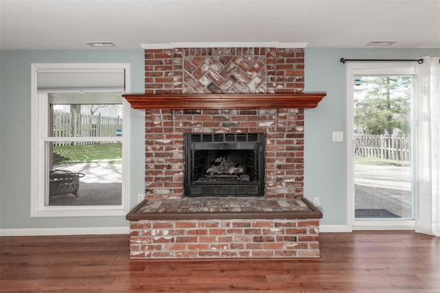 living room featuring a brick fireplace and dark wood-type flooring