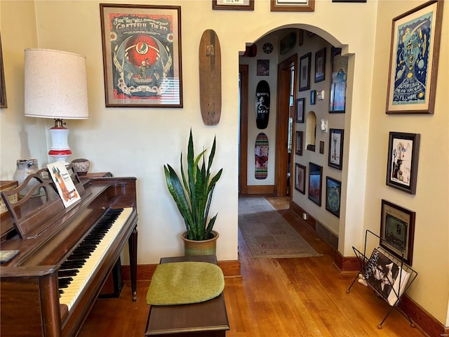 hallway featuring baseboards, arched walkways, and wood finished floors