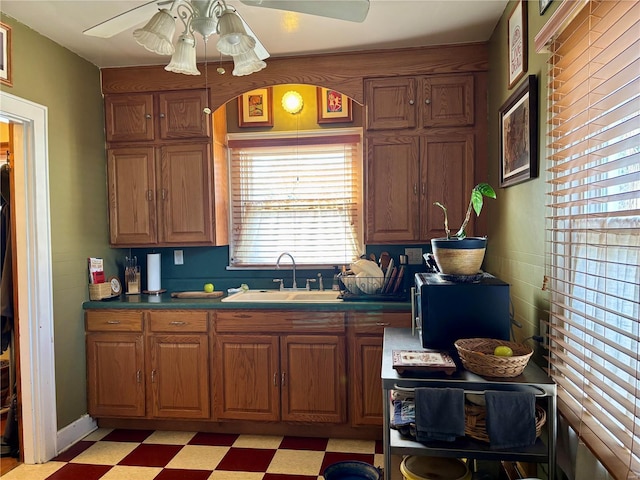 kitchen with brown cabinets, a sink, light floors, and ceiling fan