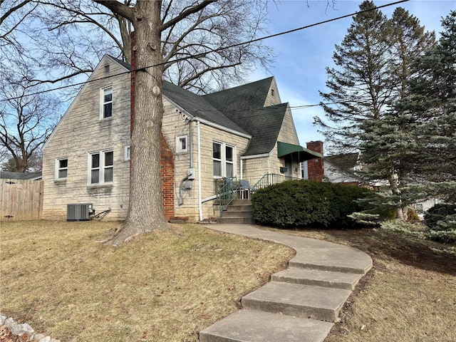 view of home's exterior with a shingled roof, a lawn, fence, cooling unit, and stone siding