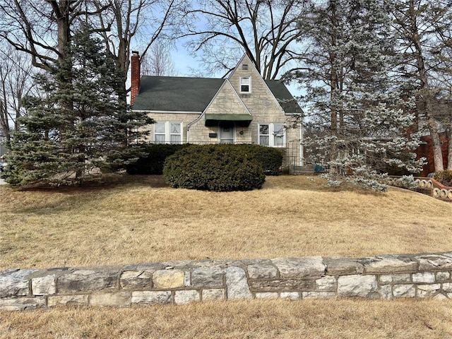 view of front of property with stone siding, a chimney, and a front yard