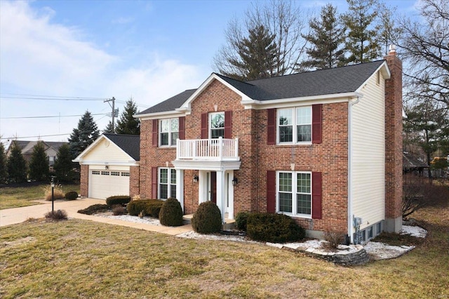 colonial home featuring a garage, a front yard, and a balcony