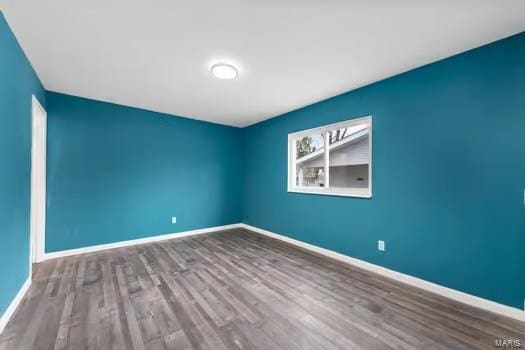 spare room featuring baseboards and wood finished floors