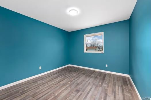 spare room with baseboards and wood finished floors