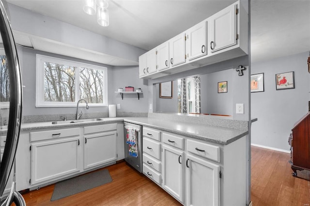 kitchen with white cabinetry, black refrigerator, sink, and kitchen peninsula