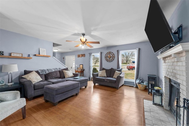 living room featuring hardwood / wood-style floors, a brick fireplace, and ceiling fan