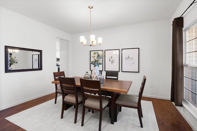 dining space featuring a chandelier, baseboards, and wood finished floors