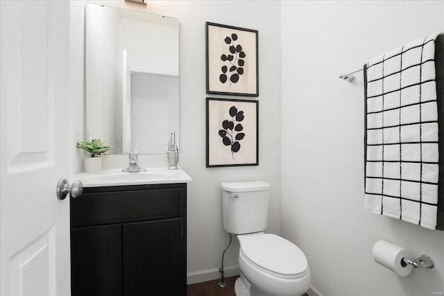 half bath with toilet, vanity, and baseboards