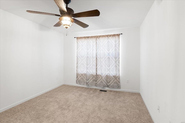 carpeted spare room with visible vents, baseboards, and ceiling fan