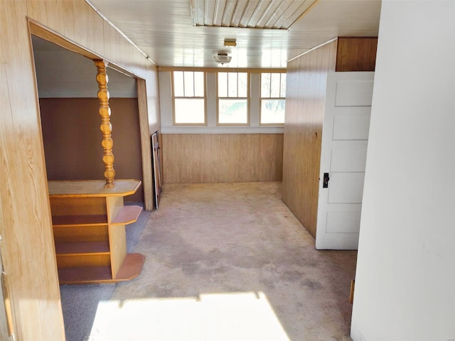 hallway with light carpet and wood walls