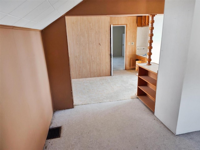 hallway with lofted ceiling and light colored carpet