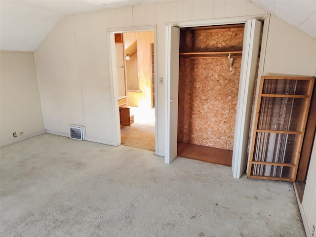 unfurnished bedroom with light colored carpet and lofted ceiling
