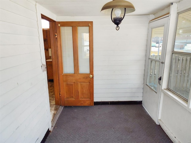 entryway featuring dark carpet and wooden walls
