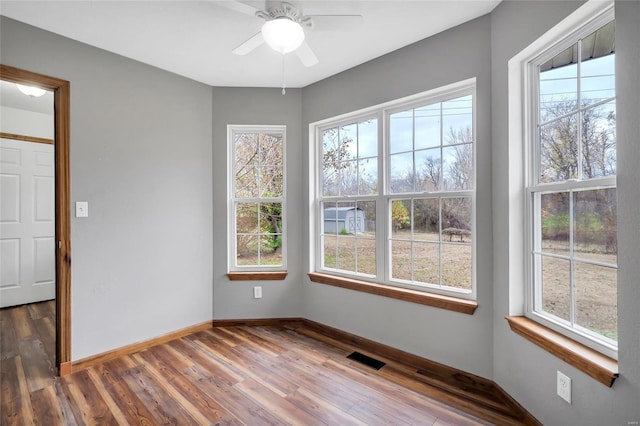 empty room featuring dark hardwood / wood-style flooring, ceiling fan, and a healthy amount of sunlight