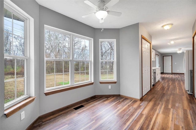 spare room with plenty of natural light, dark wood-type flooring, and ceiling fan