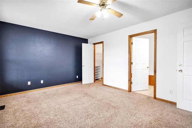 unfurnished bedroom with ensuite bathroom, light colored carpet, and ceiling fan