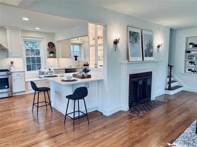 kitchen featuring white cabinets, light wood-type flooring, stainless steel gas range, and a kitchen breakfast bar