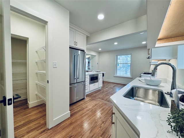 kitchen featuring sink, white cabinetry, appliances with stainless steel finishes, dark hardwood / wood-style floors, and light stone countertops