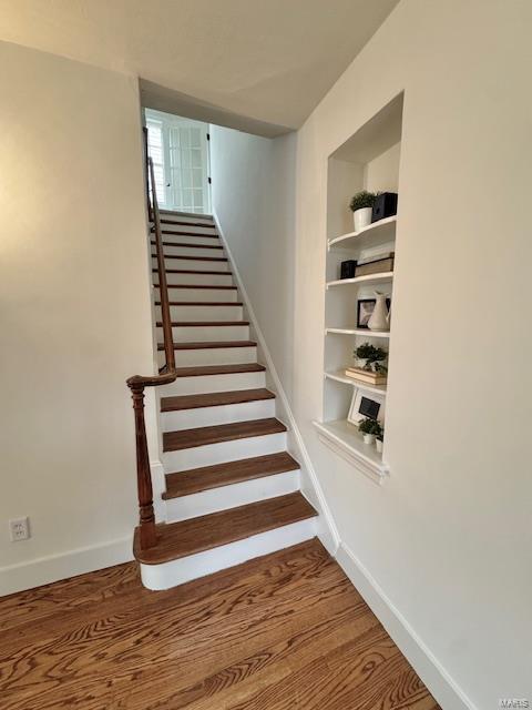 stairway featuring hardwood / wood-style floors and built in features