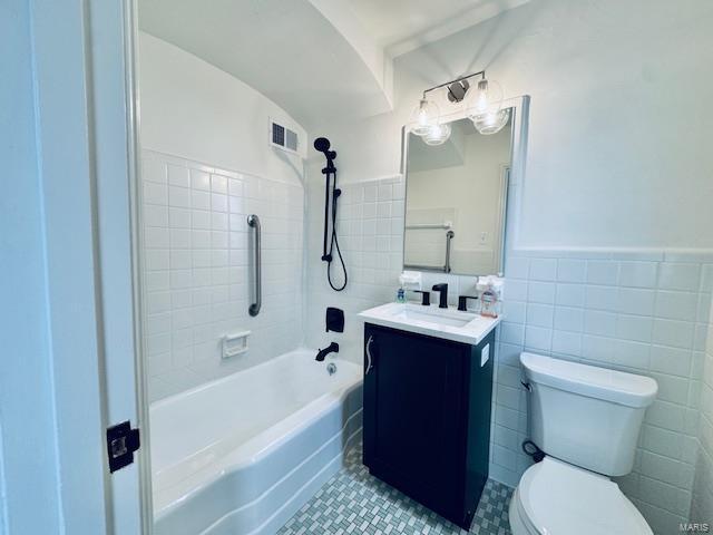 bathroom featuring tile patterned floors, vanity, toilet, and tile walls