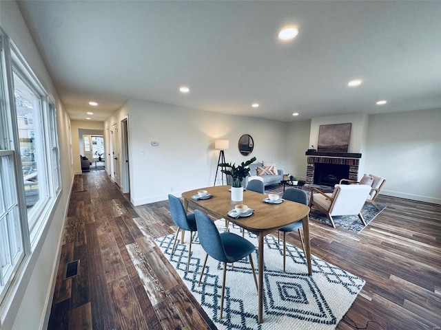 dining area featuring dark wood-type flooring and a fireplace