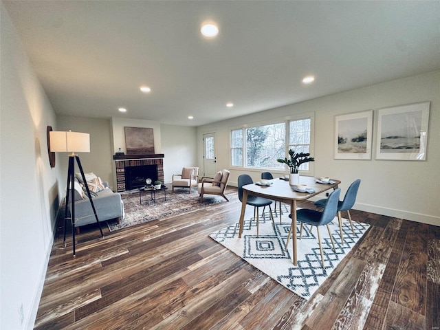 dining room with a brick fireplace and dark hardwood / wood-style floors