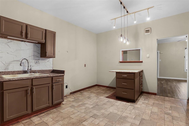 kitchen with hanging light fixtures, sink, dark brown cabinetry, and decorative backsplash