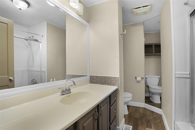 bathroom featuring hardwood / wood-style flooring, vanity, walk in shower, toilet, and a textured ceiling