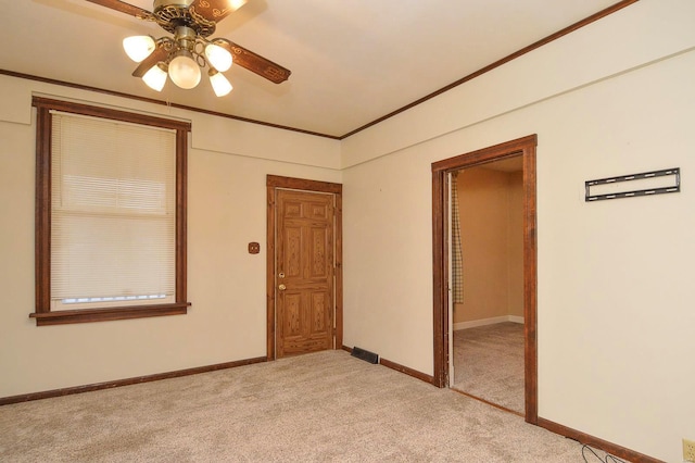 empty room featuring crown molding, light colored carpet, and ceiling fan